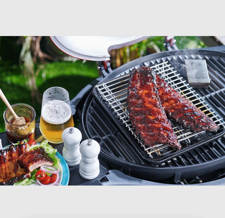 Grill tray with ribs on barbecue rack, served with beer, sauce, and salad outdoors